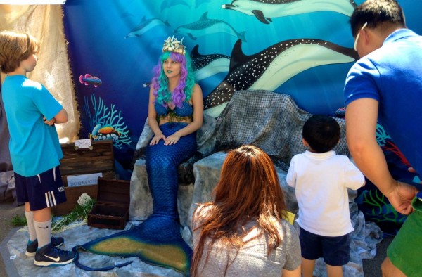 A mermaid speaks to a child at the Mer Folk booth